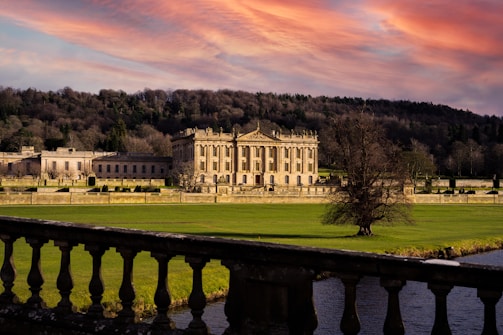 A serene dusk view of Baddiley Hall’s grand facade framed by softly lit gardens.