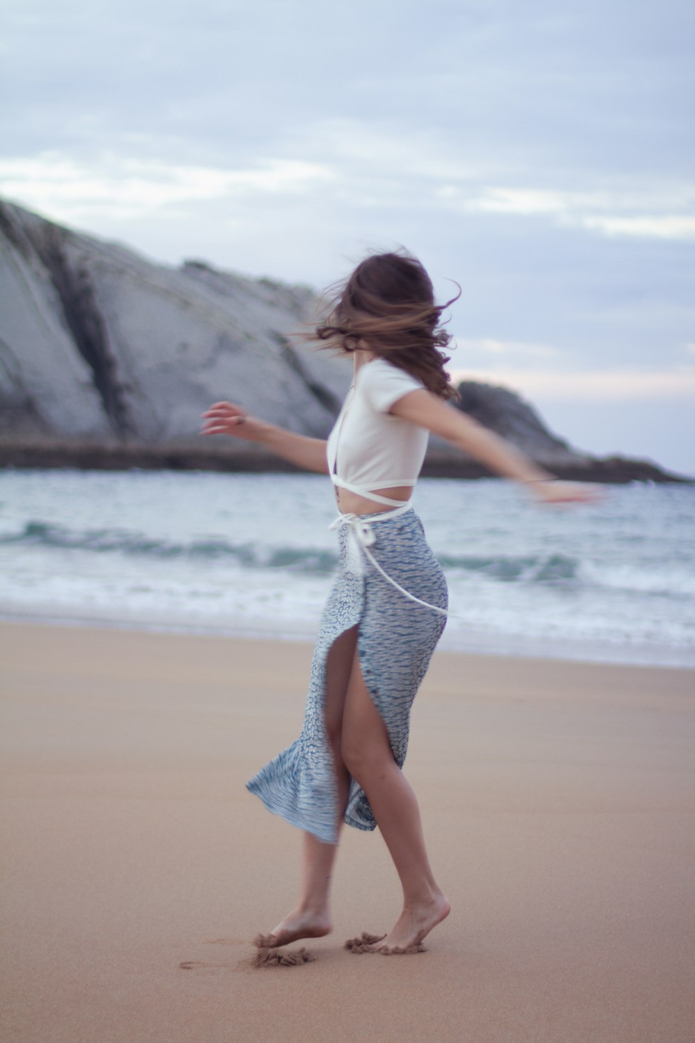 a woman walking on a beach next to the ocean