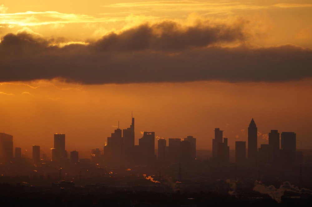 the sun is setting over a city with tall buildings