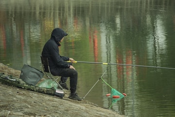 a man sitting next to the water river fishing