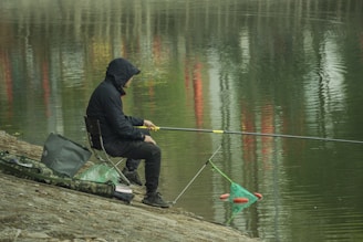 a man sitting next to the water river fishing