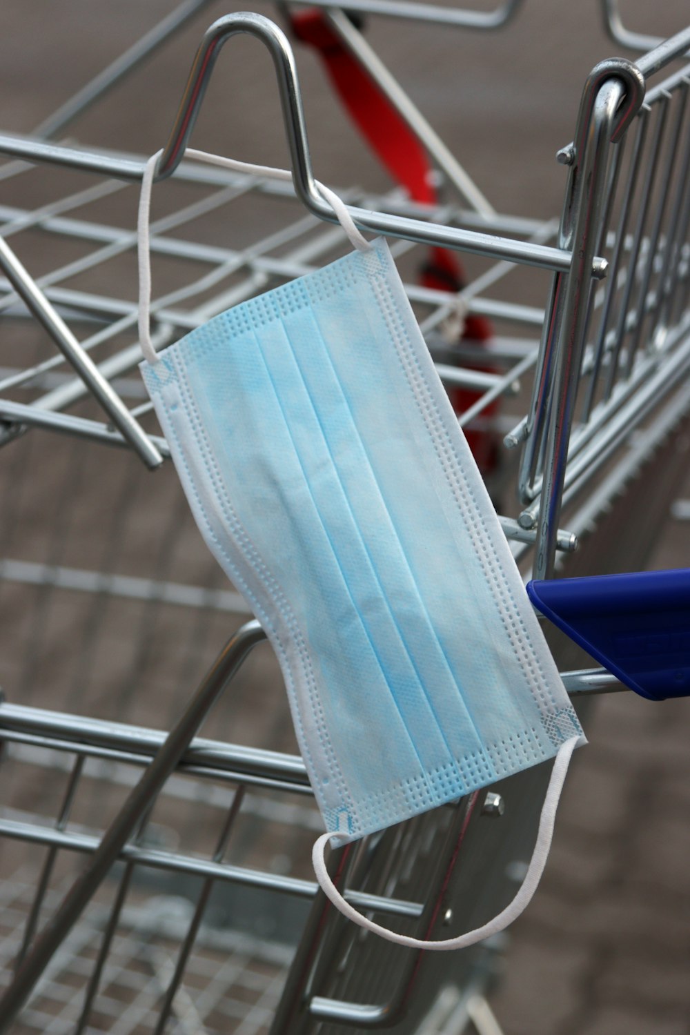 a blue face mask hanging from a shopping cart