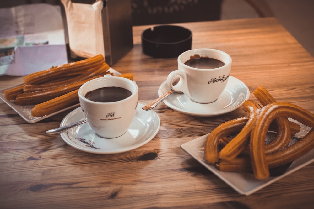 two cups of coffee and some churros on a table