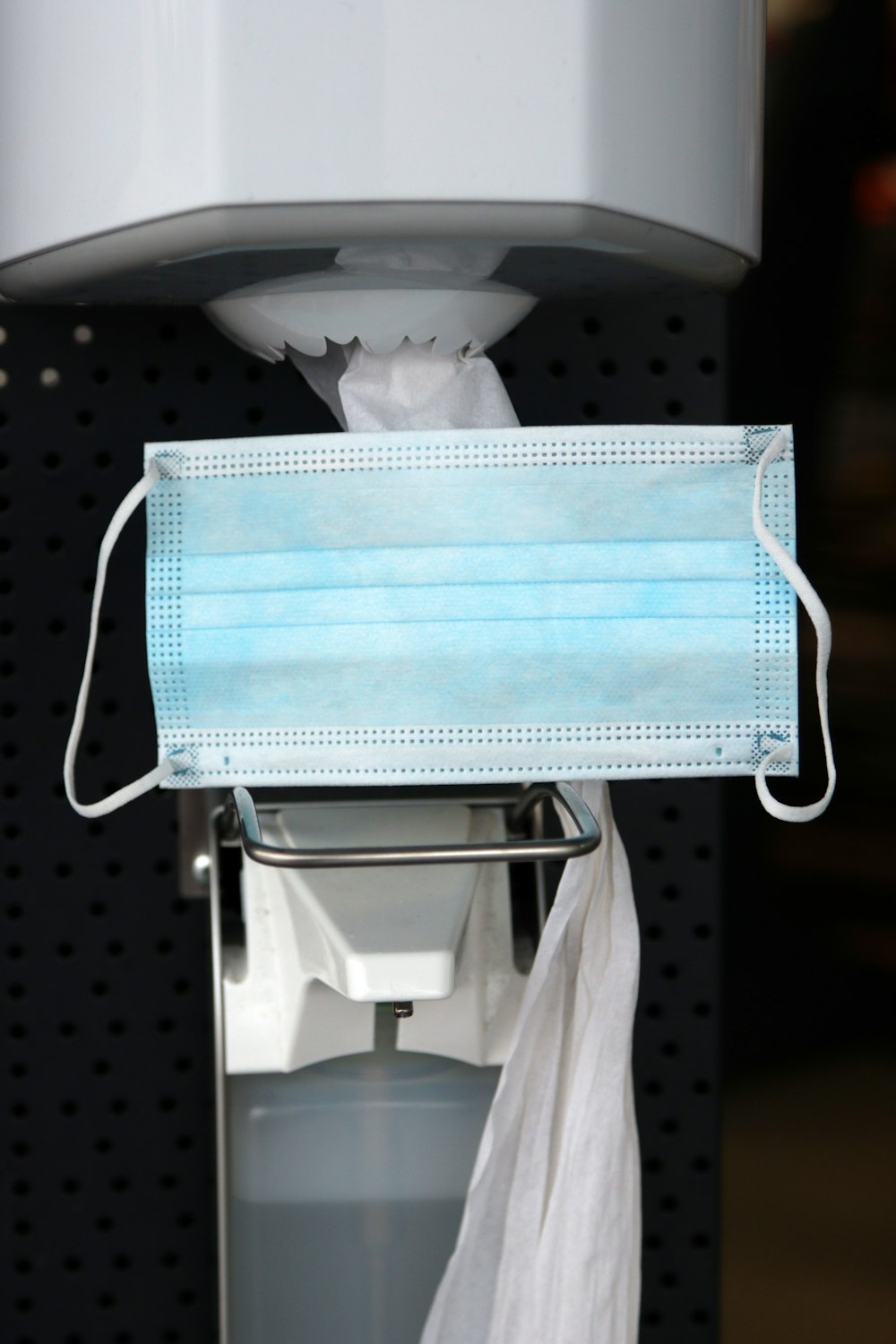 a disposable face mask hanging from a dispenser