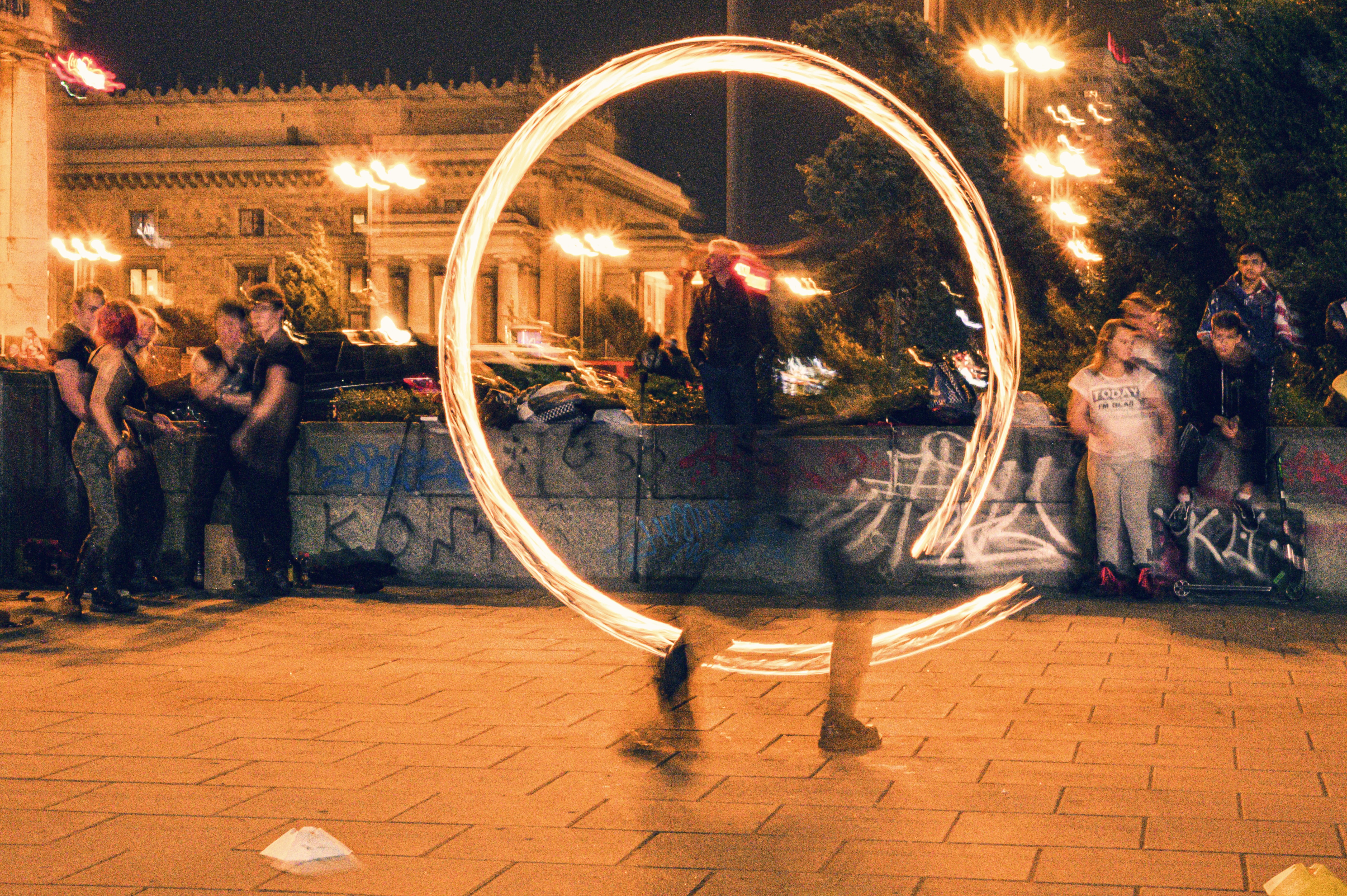 Poi spinner performing with glowing circular poi patterns outdoors at night