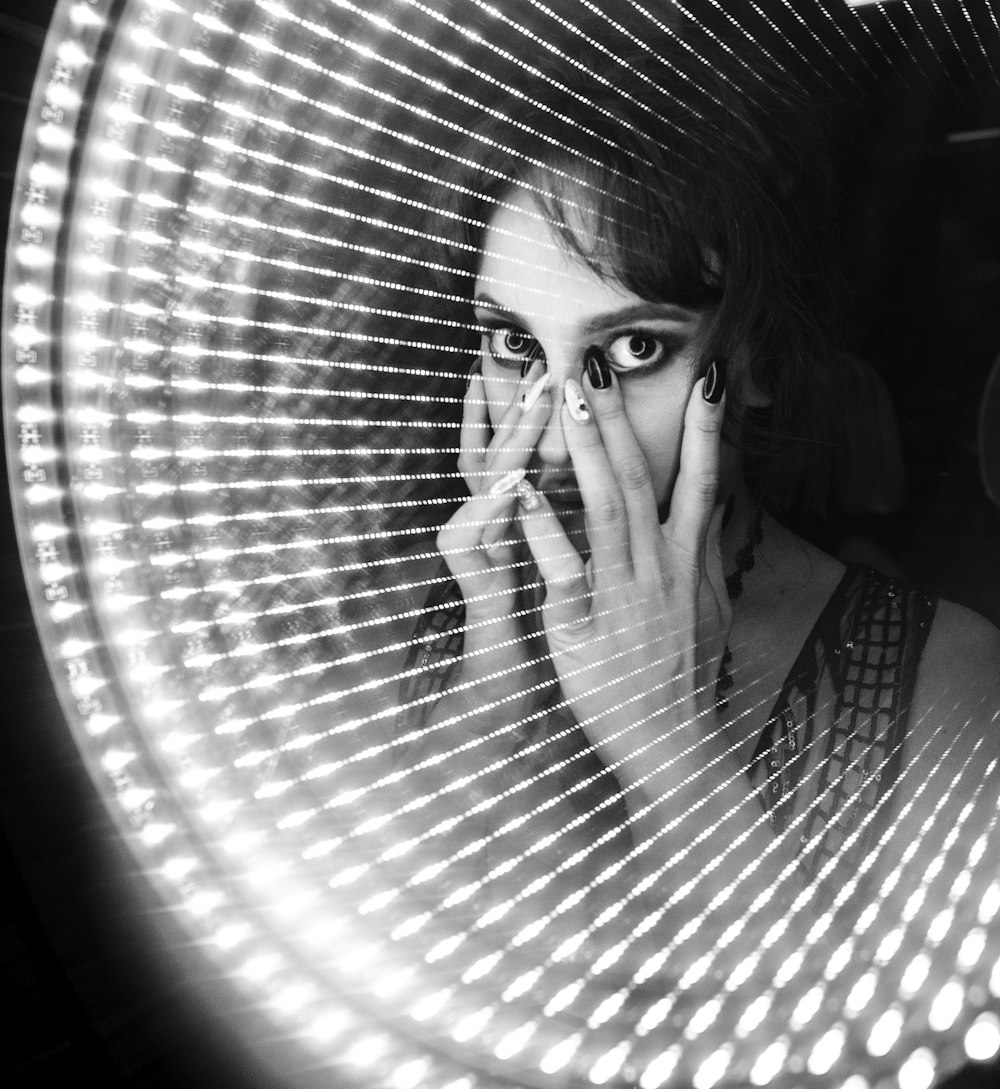 a woman holding her face in front of a mirror