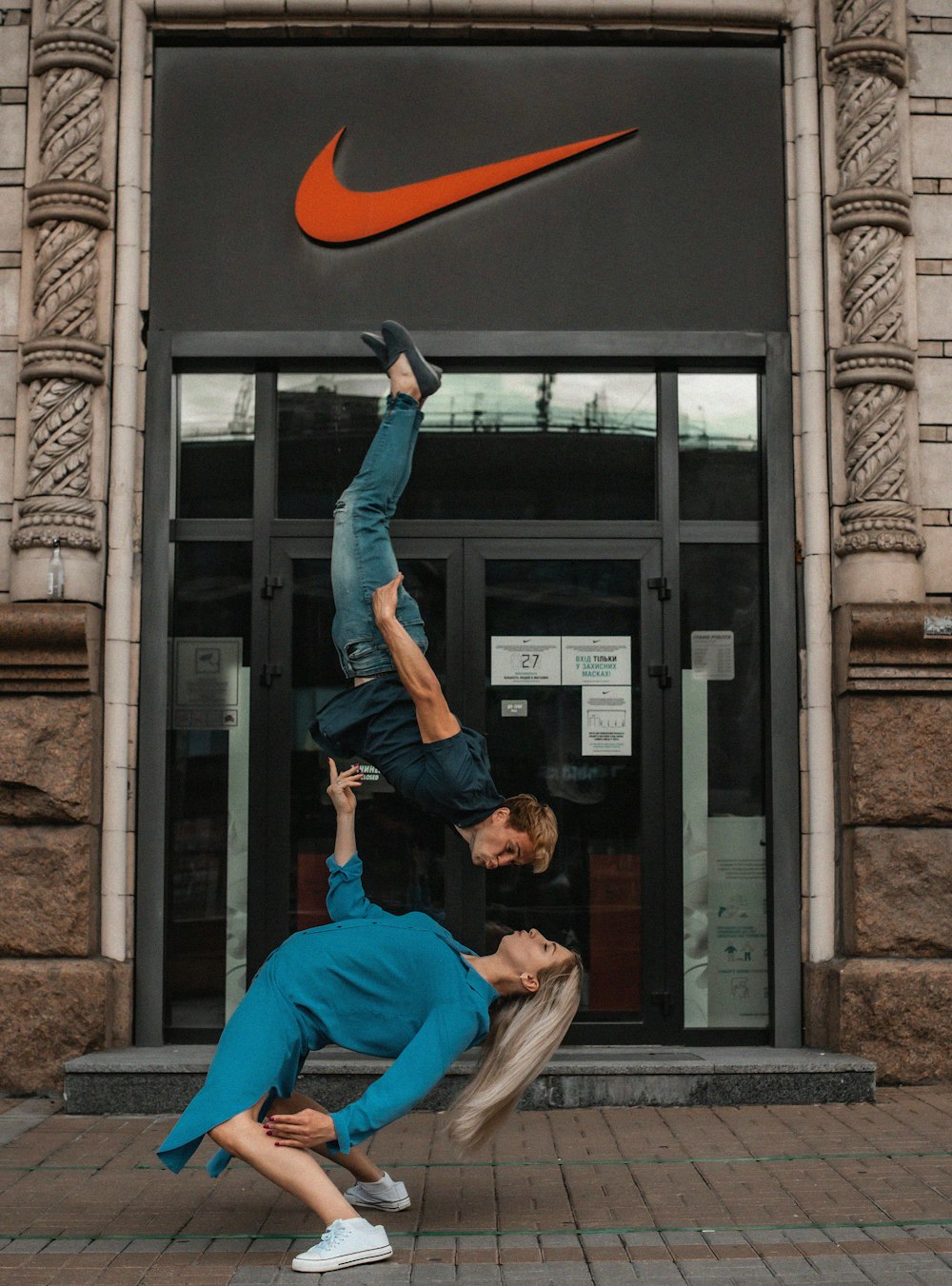 two people doing a handstand in front of a building