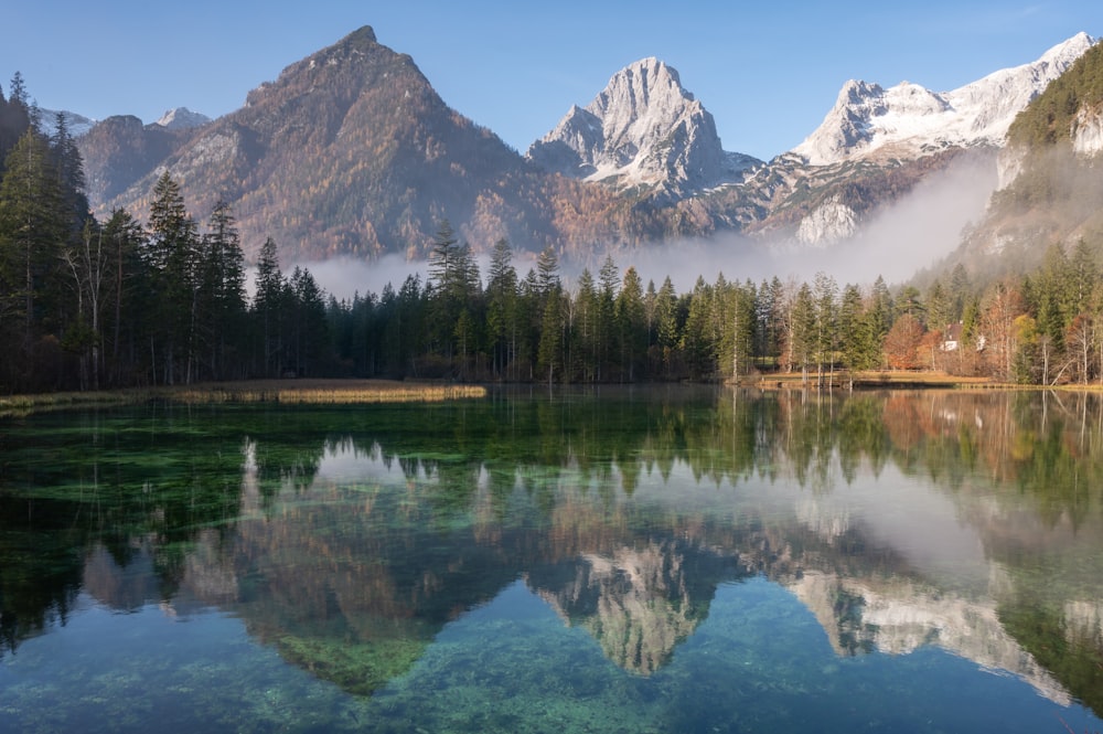 a lake surrounded by mountains with a forest in the foreground