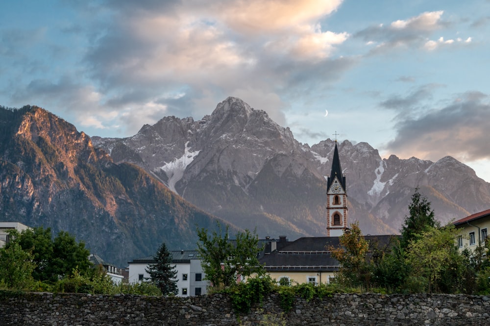 a church with a steeple in front of a mountain range