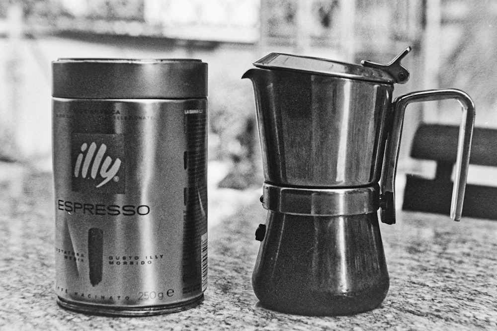 a black and white photo of a coffee maker and a can of coffee