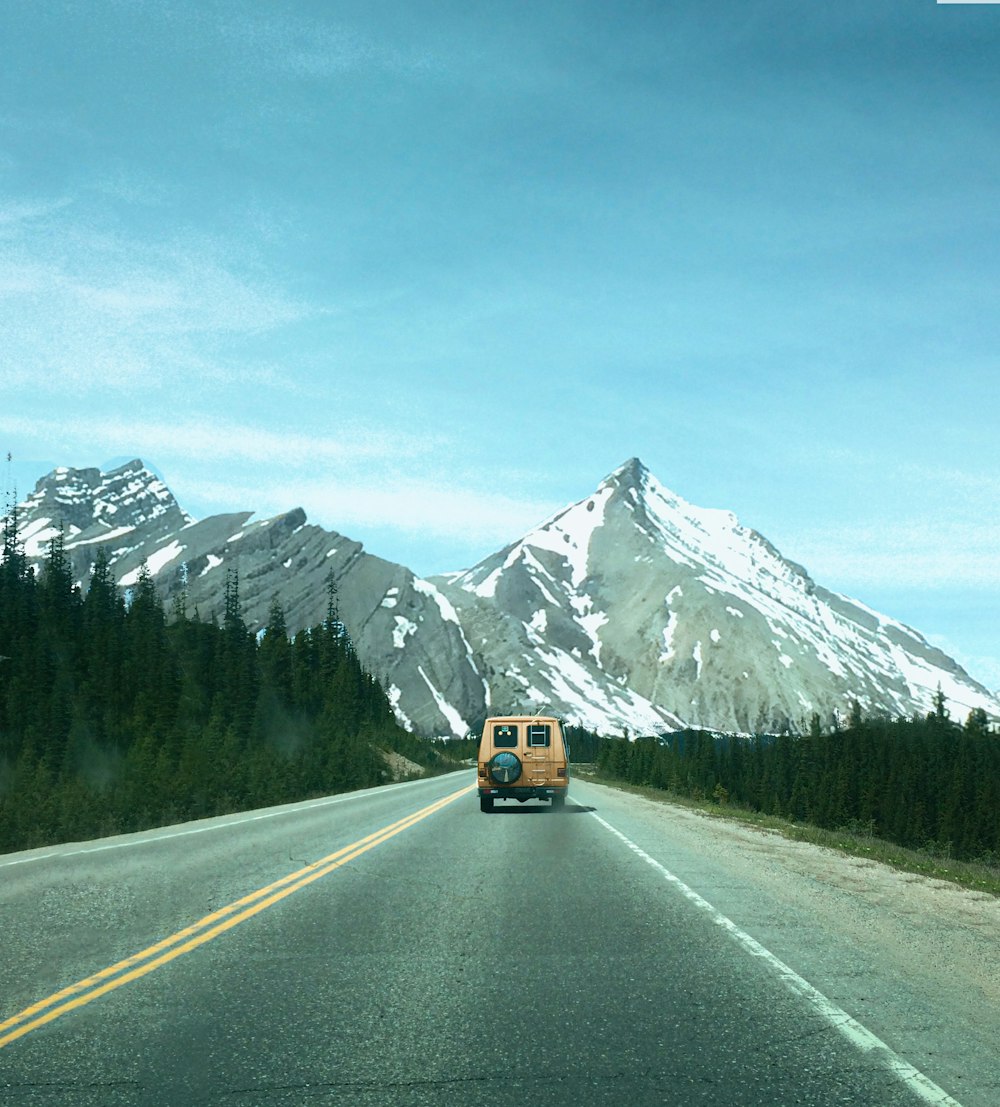 a van driving down a road with a mountain in the background