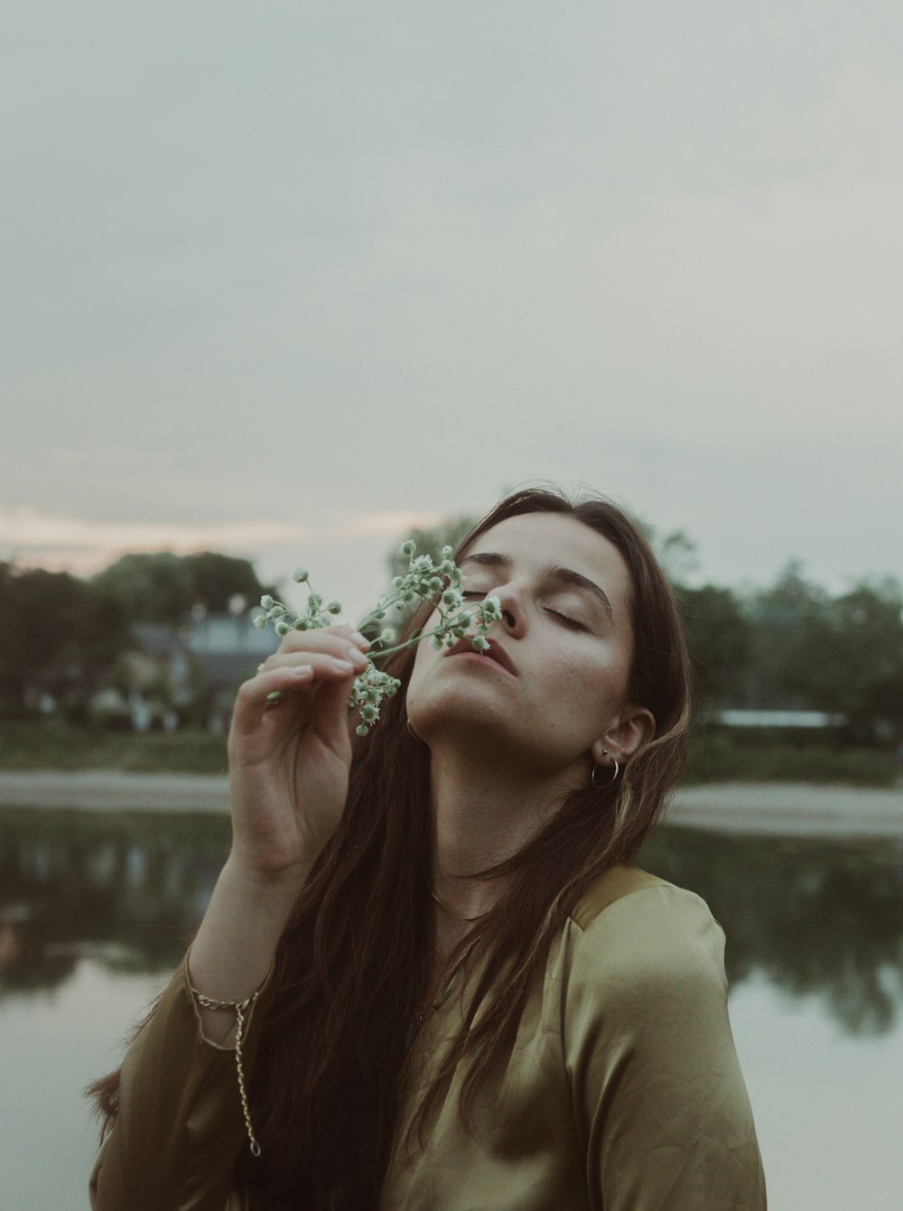 a woman with long hair holding a flower in front of her face