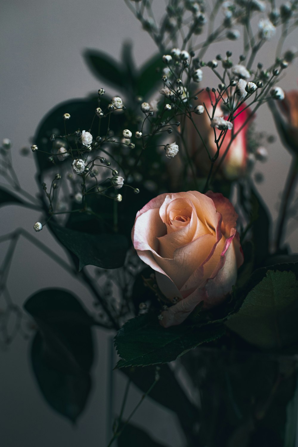 a vase filled with flowers and greenery on top of a table