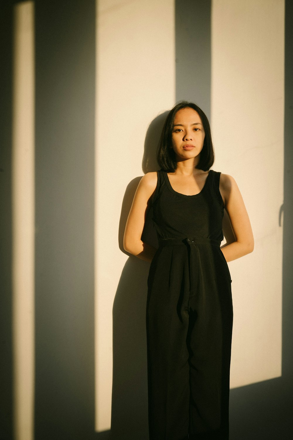 a woman standing in front of a wall with her hands on her hips