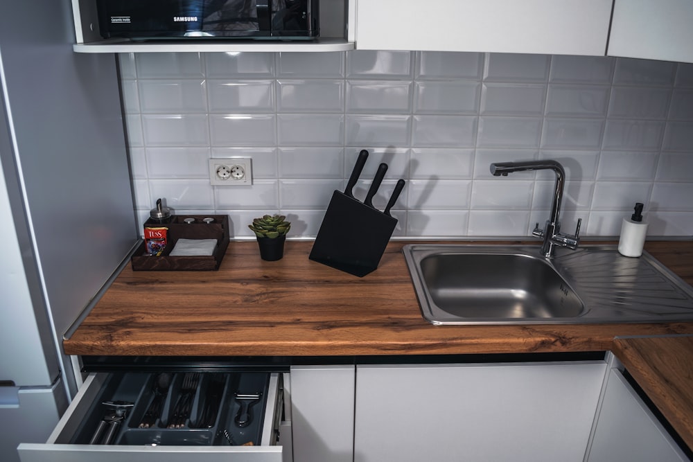 a kitchen with a sink, microwave and a cutting board