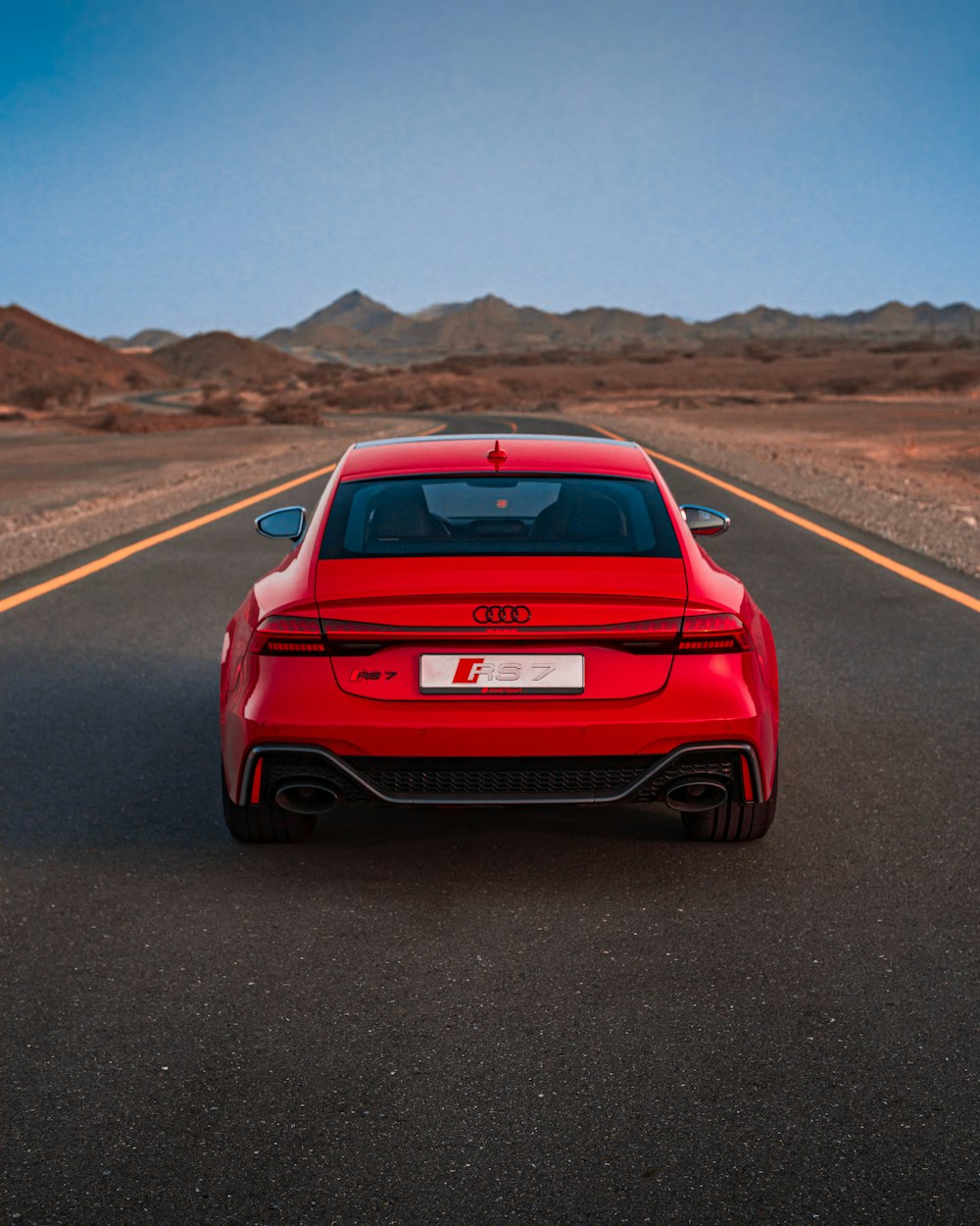 a red sports car driving down a desert road