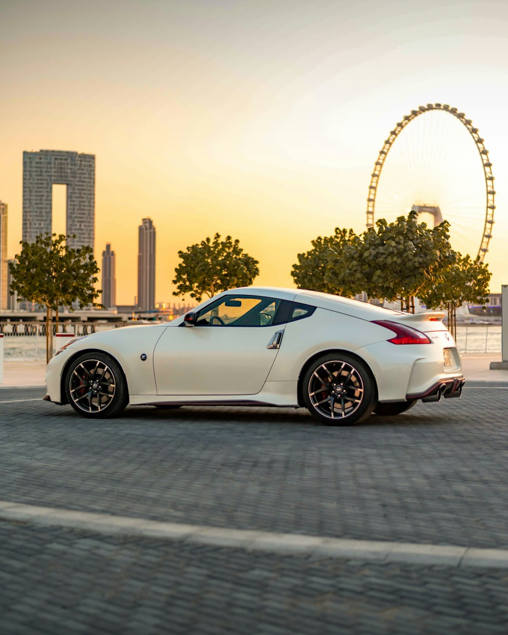 a white sports car parked in front of a ferris wheel