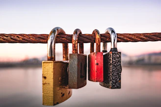 four padlocks attached to a rope near a body of water