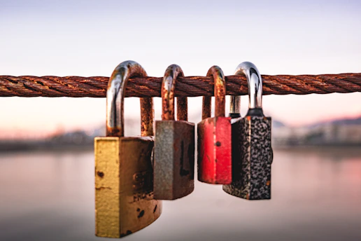 four padlocks attached to a rope near a body of water