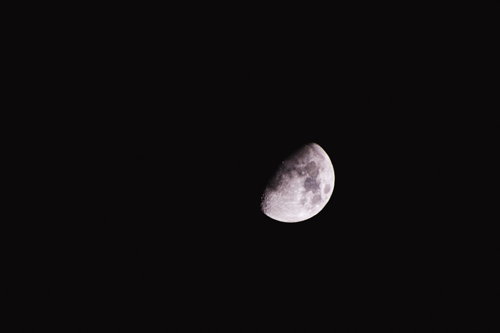 a half moon is seen in the dark sky