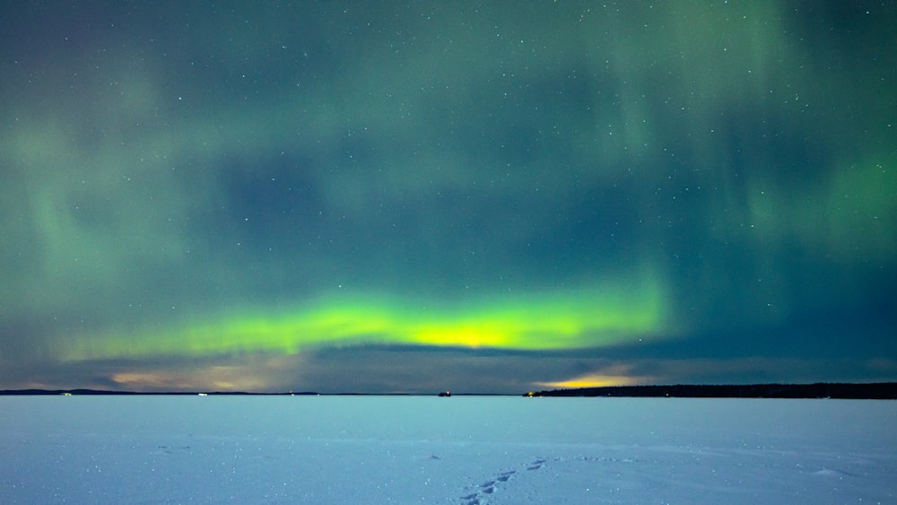 Eine leuchtend grüne und gelbe Aurora über einem verschneiten Feld