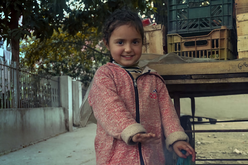 a little girl standing next to a wooden table