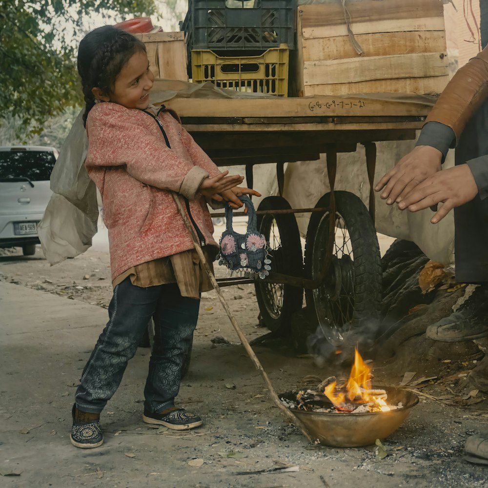 a little girl standing next to a fire