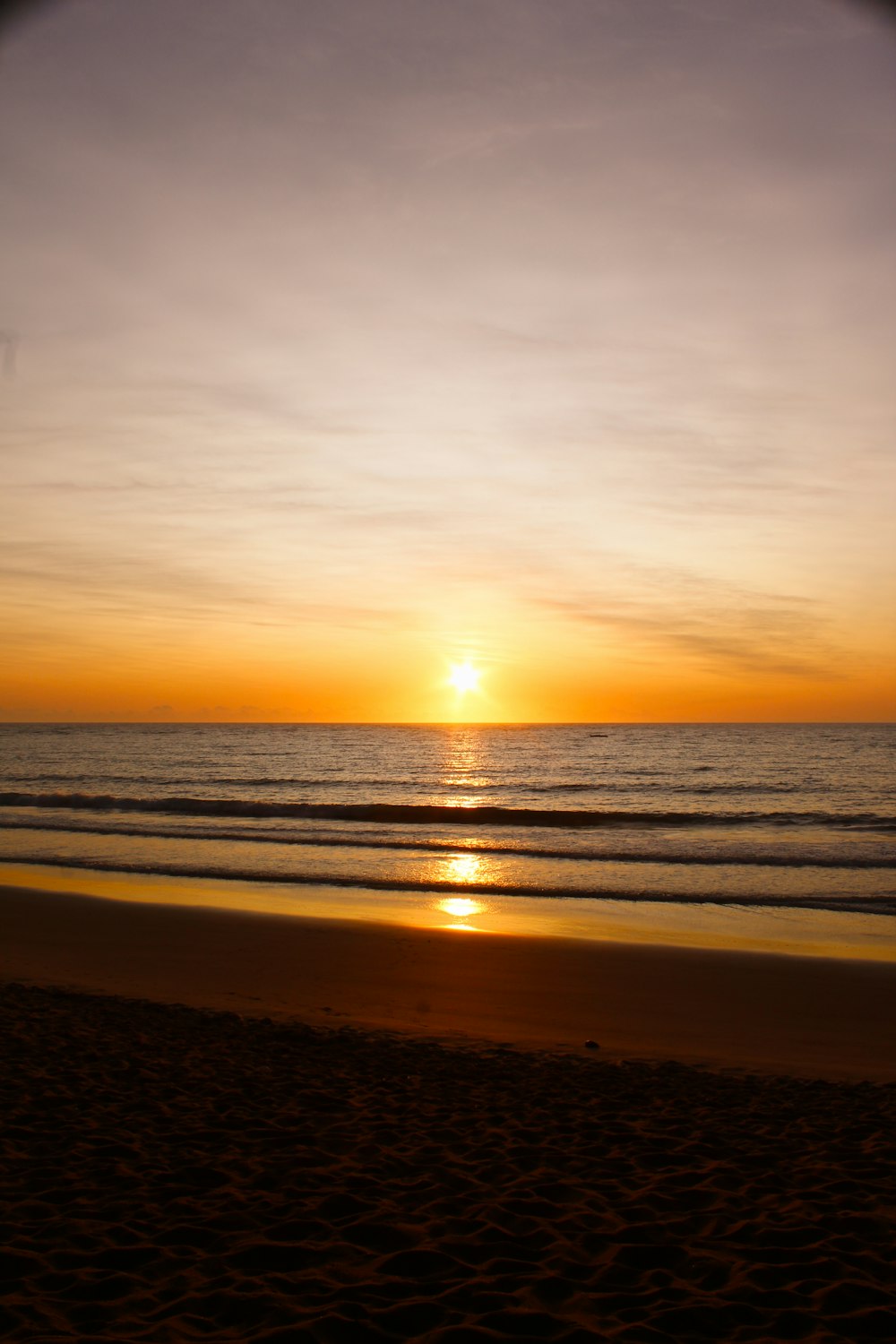 the sun is setting over the ocean on the beach