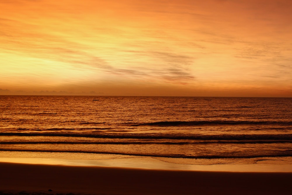 Una vista del tramonto di una spiaggia con onde che entrano