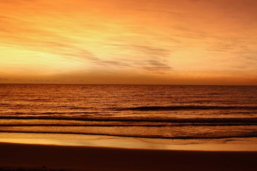 a sunset view of a beach with waves coming in