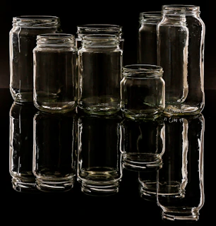 Close-up of sleek glass jars with custom caps reflecting light, arranged neatly on a wooden surface.