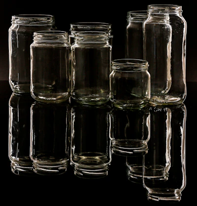 Close-up of sleek glass jars with custom caps reflecting light, arranged neatly on a wooden surface.