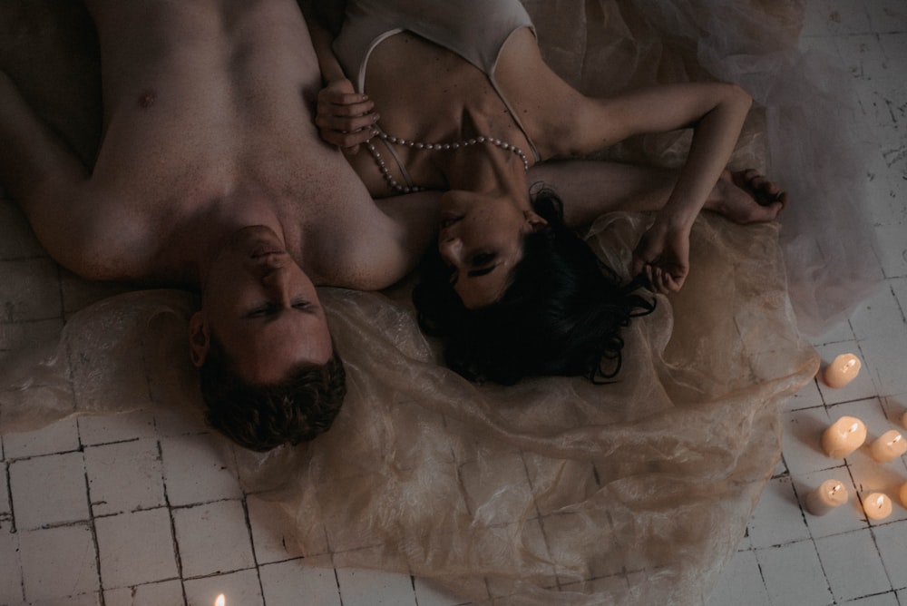 a man and a woman laying on the floor next to candles
