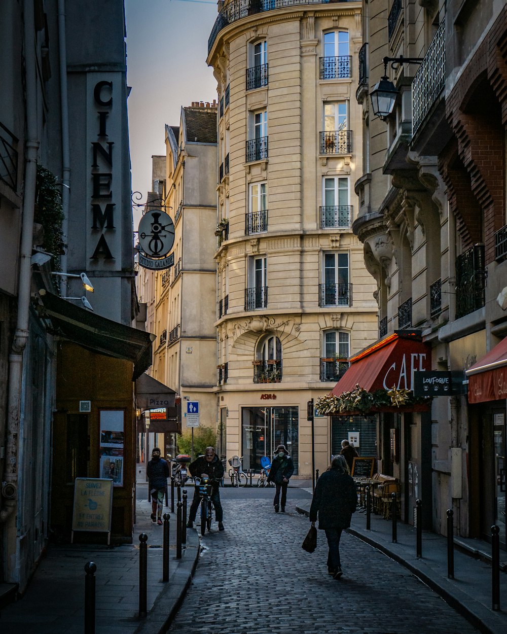 a group of people walking down a street next to tall buildings