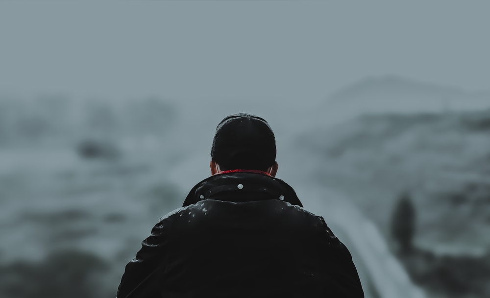 a man in a black jacket looking out over a snowy landscape