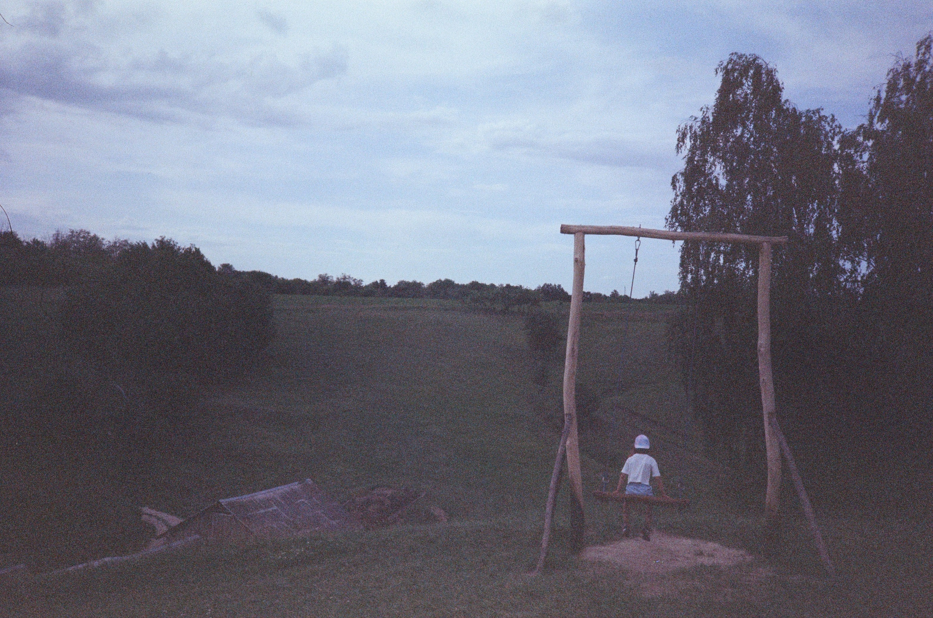 a person sitting on a swing in a field