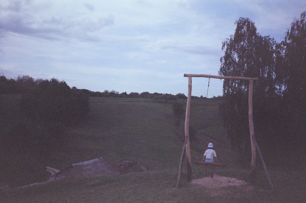 a person sitting on a swing in a field