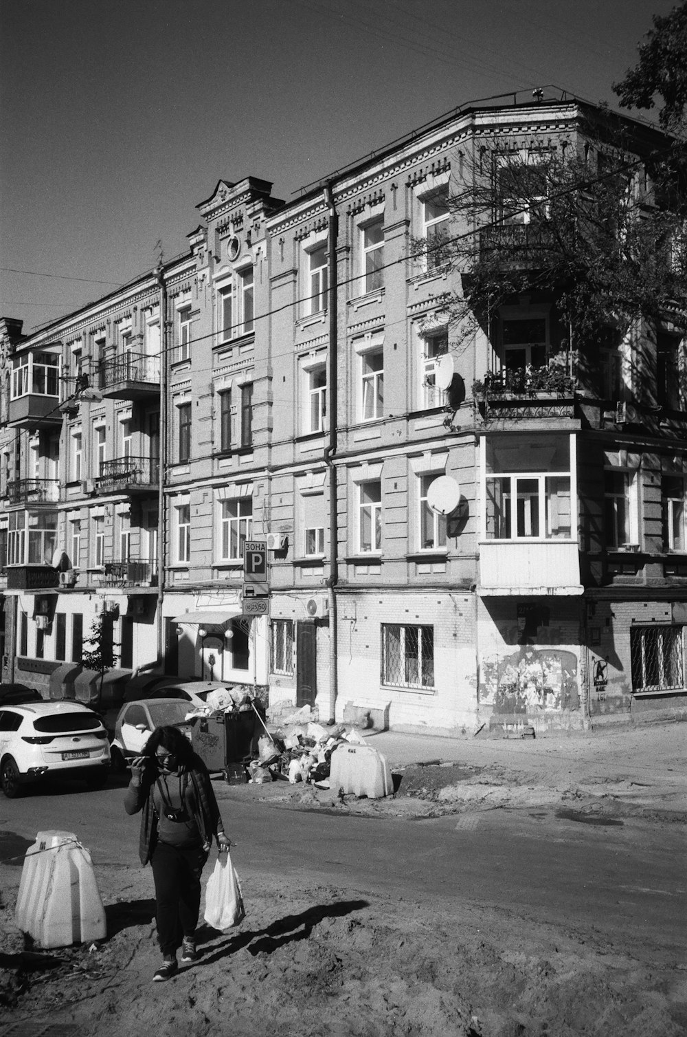 a woman walking down a street past a tall building