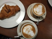 Freshly brewed coffee with a croissant on a rustic wooden table.