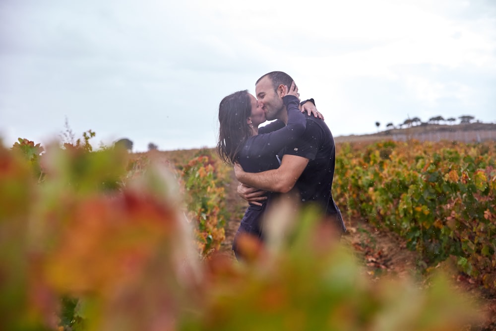 a man and woman kissing in a field of flowers