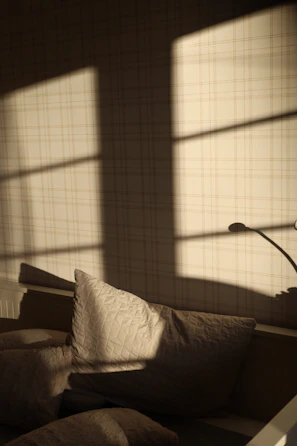 Soft morning light streaming through a window onto a cozy blush-toned reading nook.