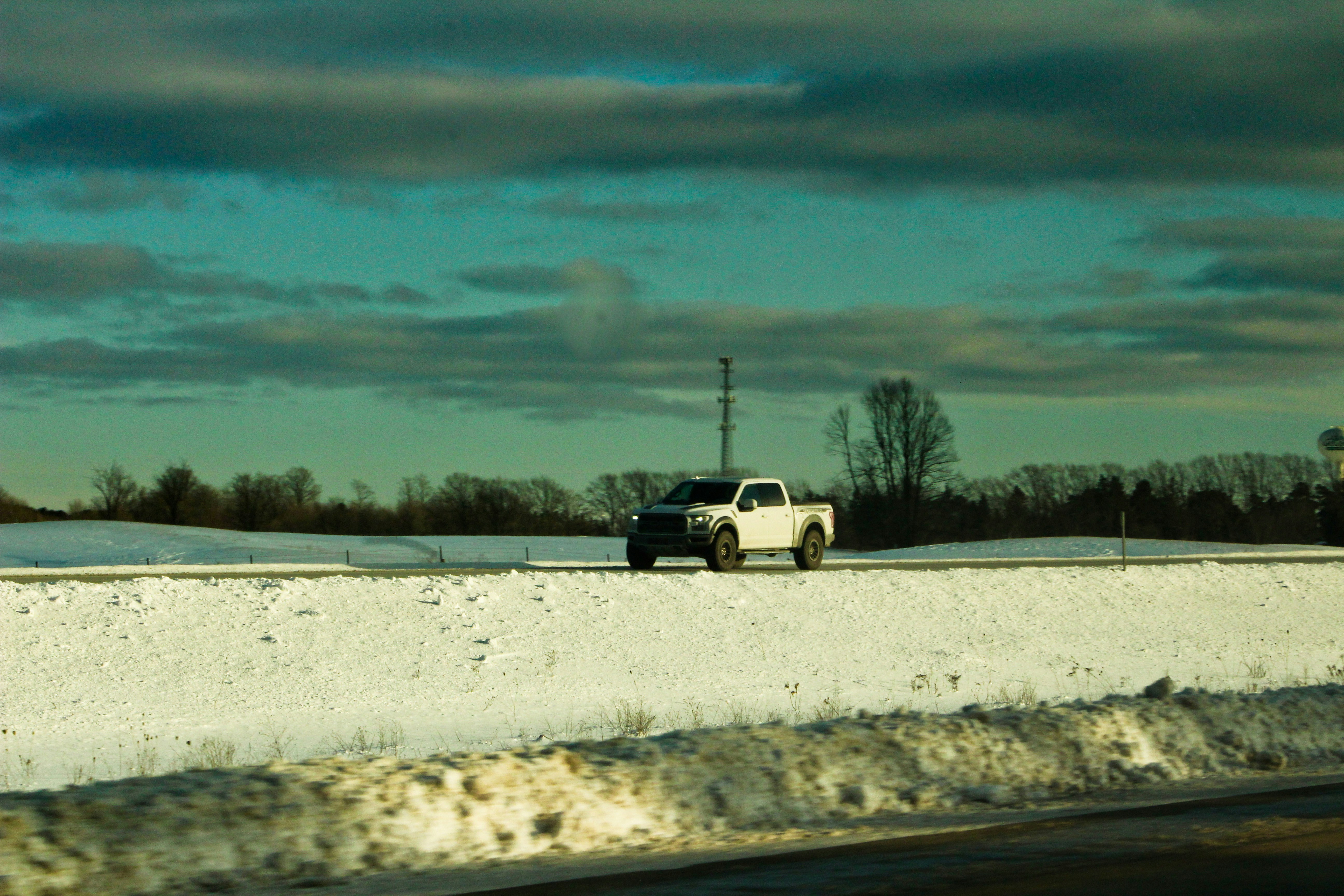 a white truck driving down a snow covered road