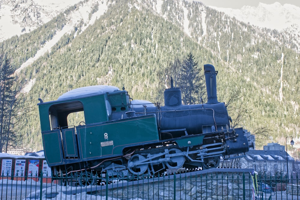 an old train is parked in front of a mountain