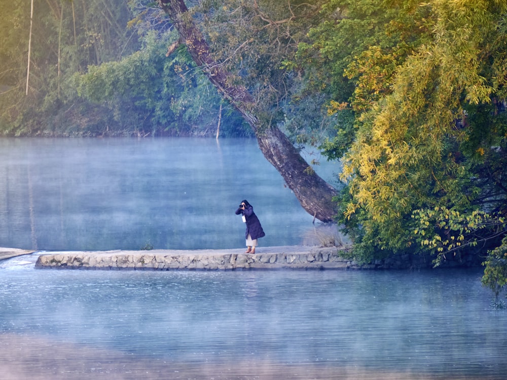 a person standing on a stone wall next to a body of water