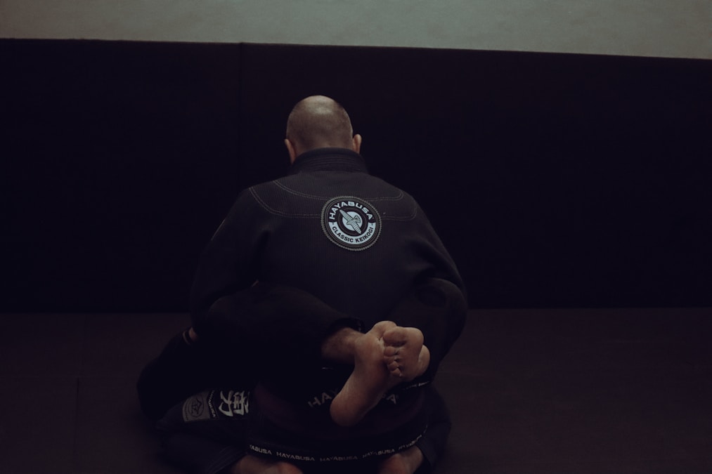 A BJJ athlete in a focused stance preparing for a no-gi grappling exchange on the mat