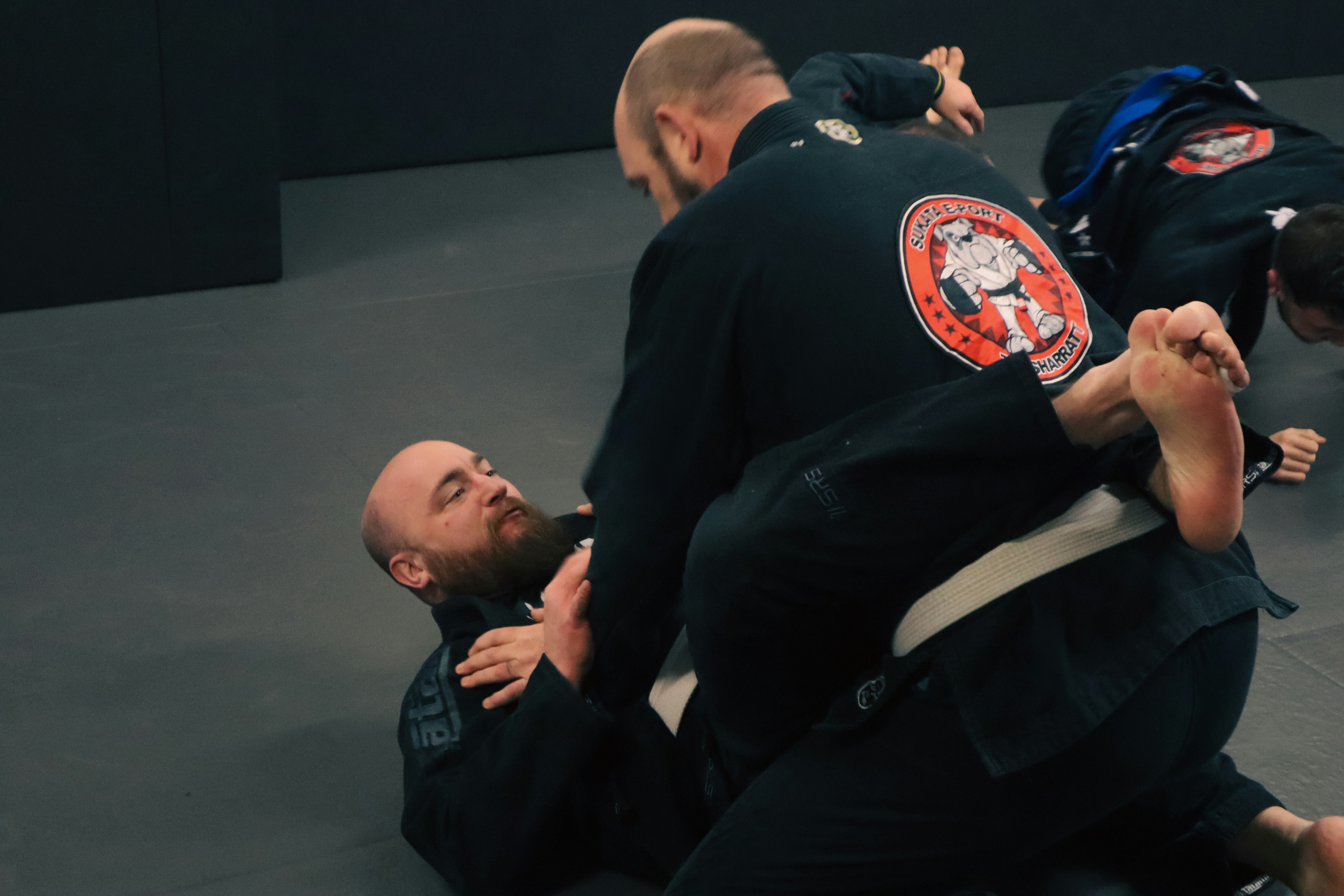 a man in a black jacket is doing a side control on another man in a