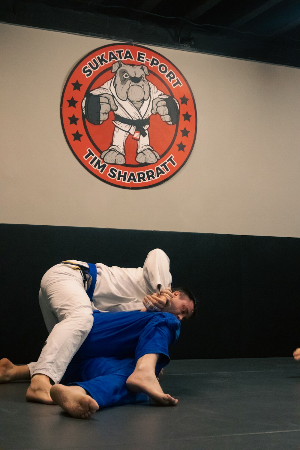 a man in a white shirt and blue pants is on a black mat