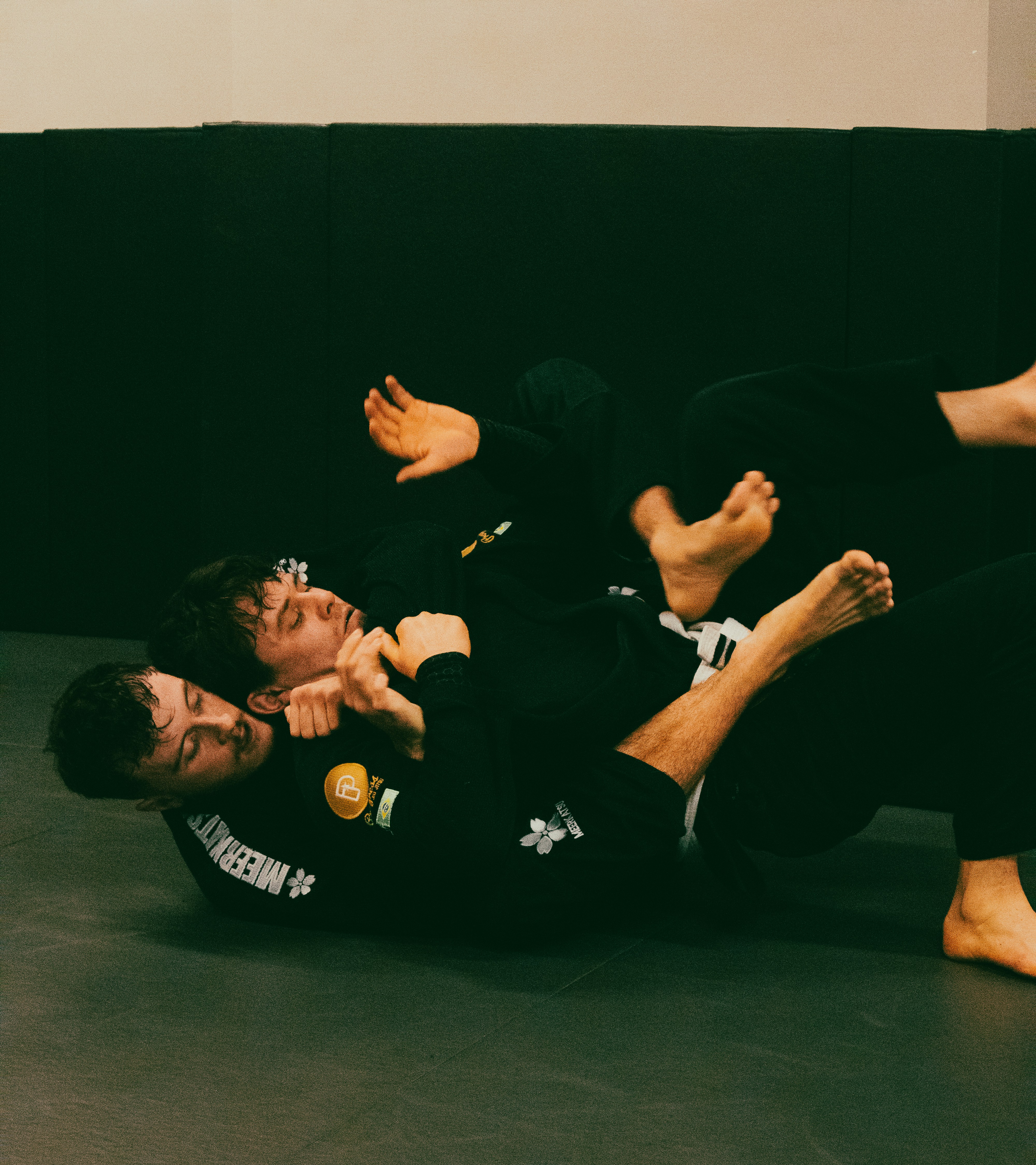 two men in black shirts and black pants on a black mat