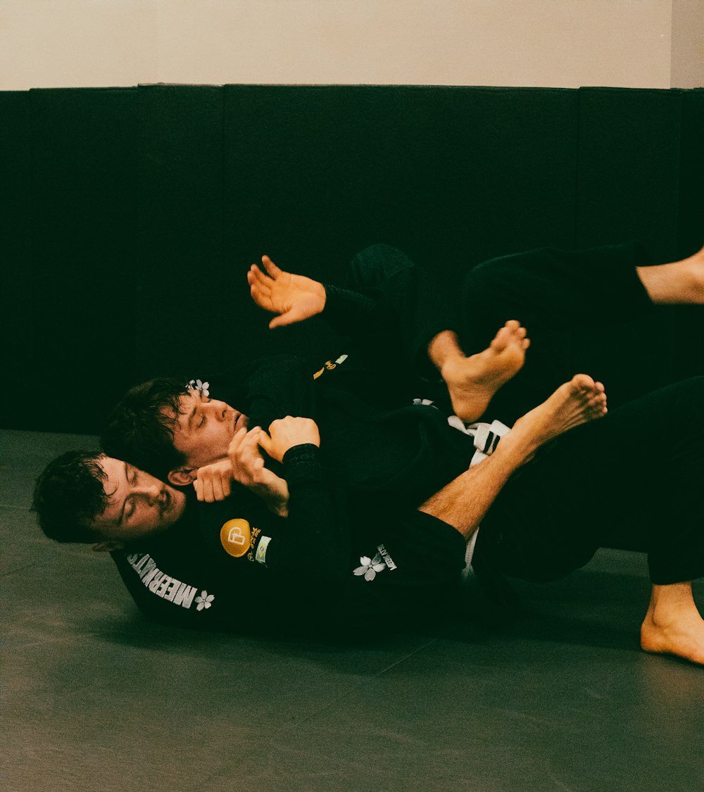 two men in black shirts and black pants on a black mat