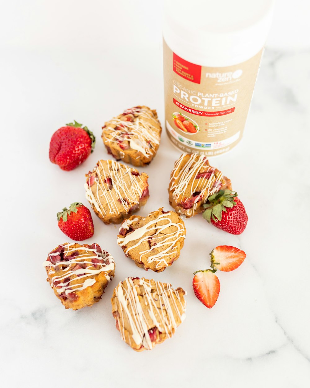 a table topped with cookies and strawberries next to a bottle of syrup